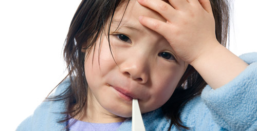 Little girl, clutching her forehead with a thermometer in her mouth